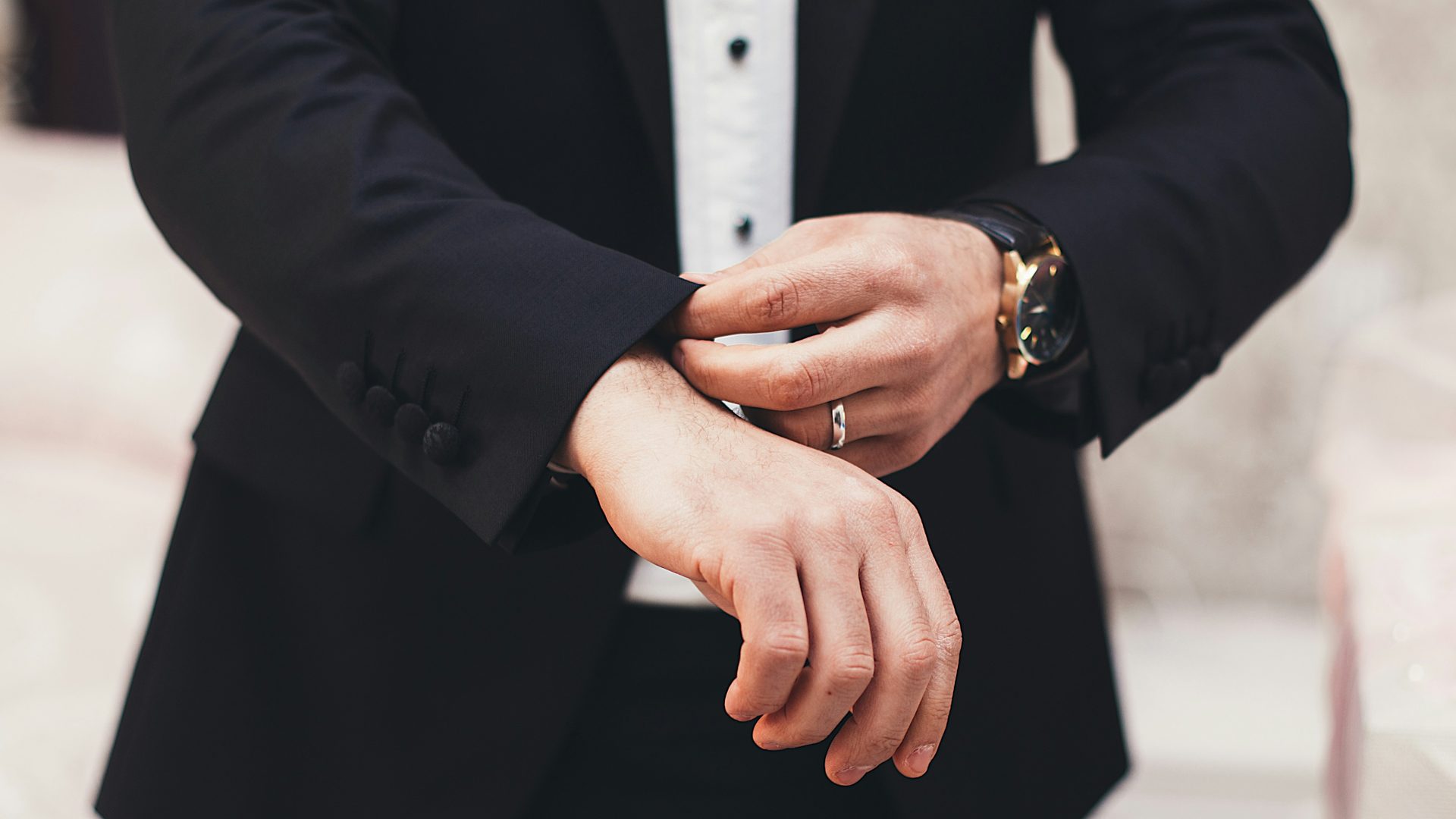 Las manos de un hombre ajustando los puños de su traje negro.